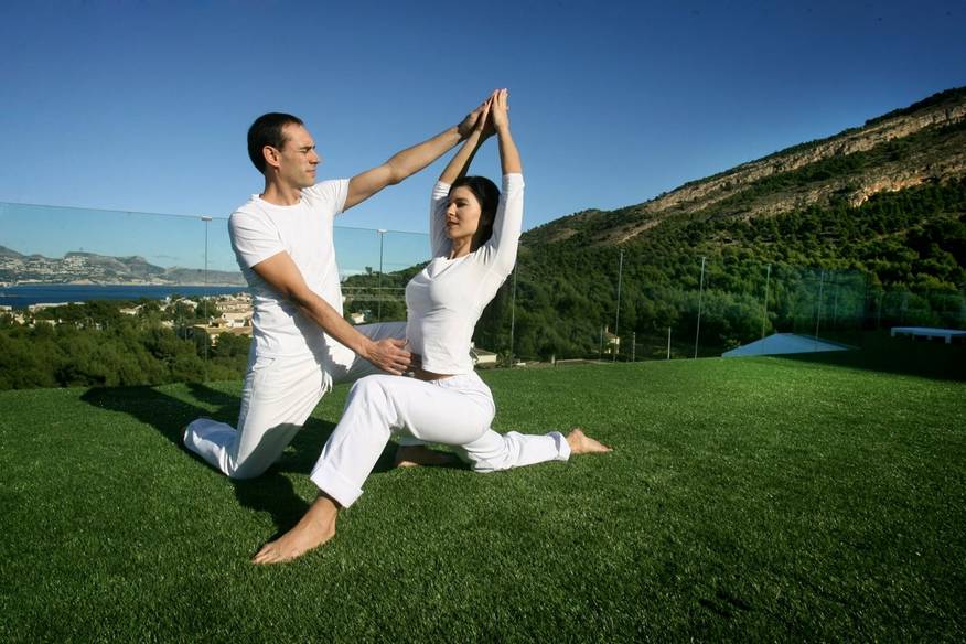Woman being taught yoga outside by an instructor at SHA Wellness Clinic in Alicante, Spain